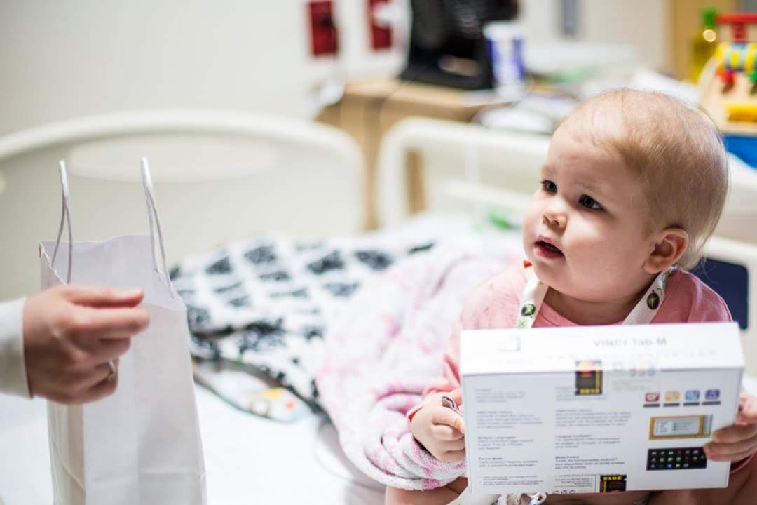 A young patient receiving a handheld gaming device at the bedside